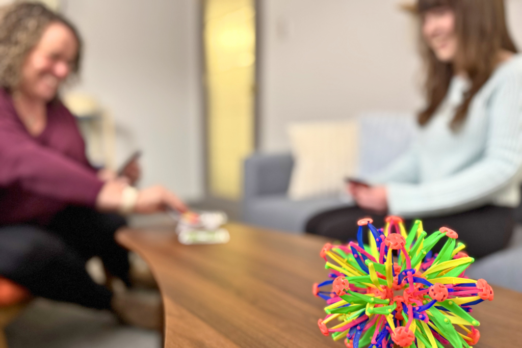 A therapist and youth playing cards in a therapist office while smiling